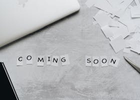A creative arrangement with paper cutouts spelling 'Coming Soon' on a textured surface.